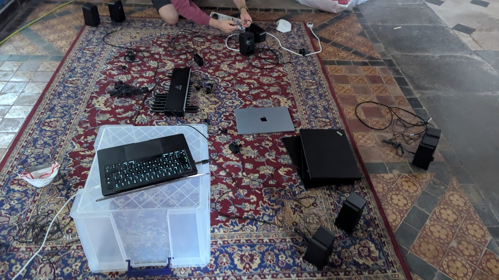 Image of a carpet on the church floor we did this on, sound board and laptop open, partner wiring things together, speakers strewn about n' stuff